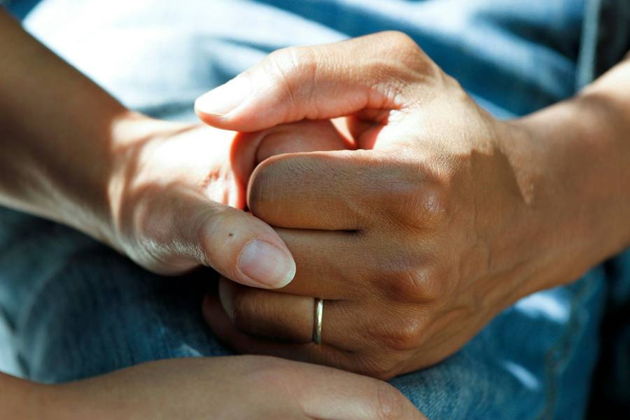 Dłoń opiekunki trzyma dłoń seniorki
